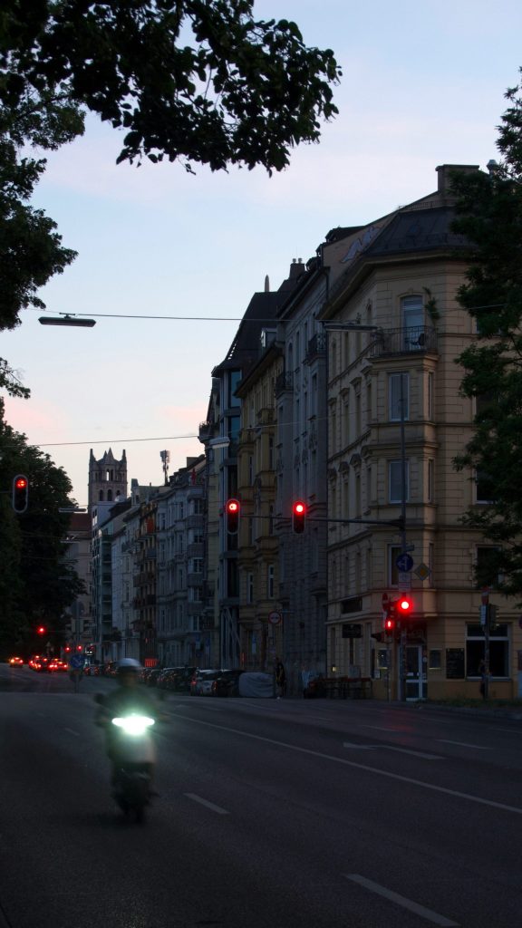 Ein Motorradfahrer fährt in der Dämmerung eine Straße in der Stadt entlang.